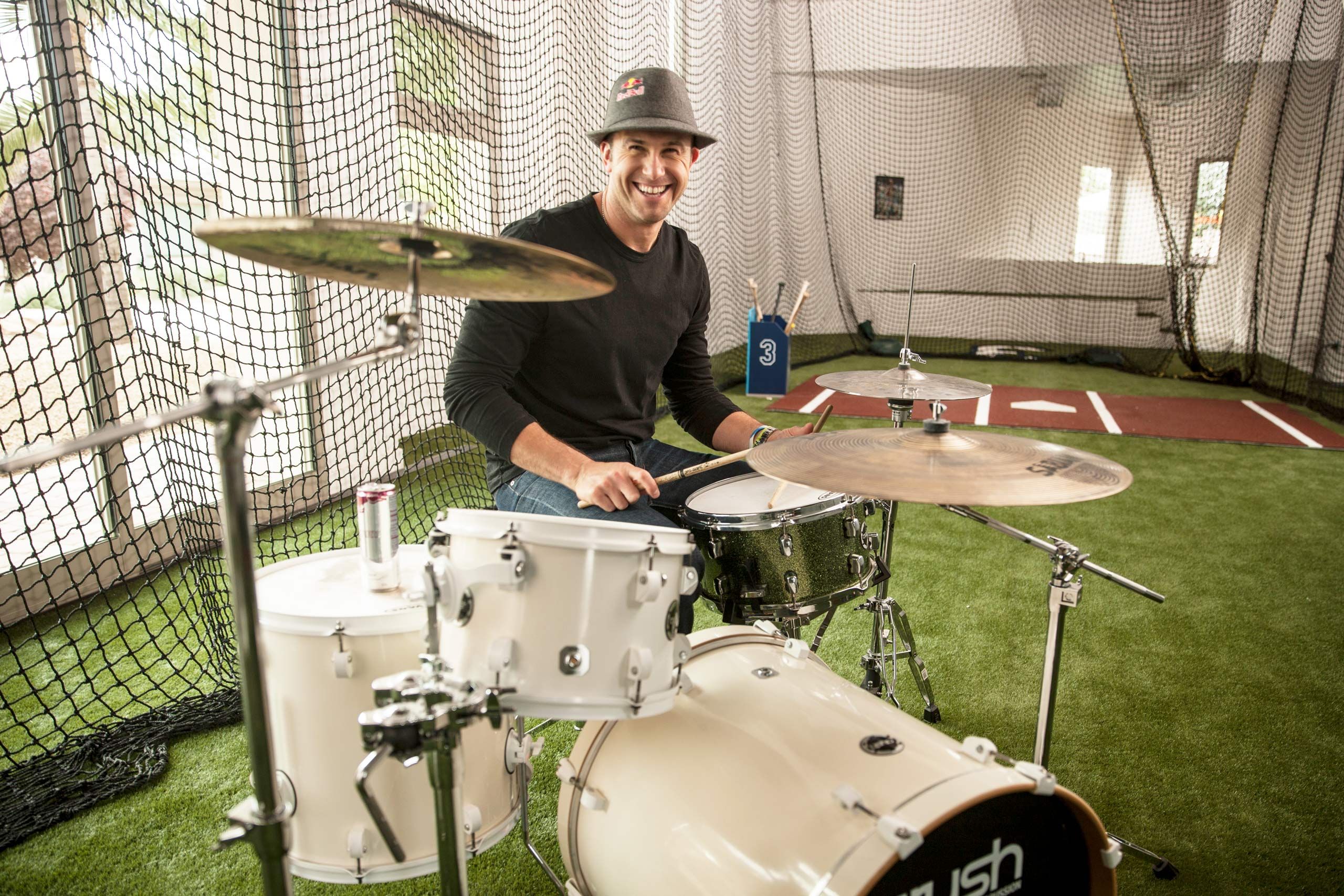 Baseball player Evan Longoria playing drums at home in his batting cage. Lifestyle Editorial Photographer in Florida