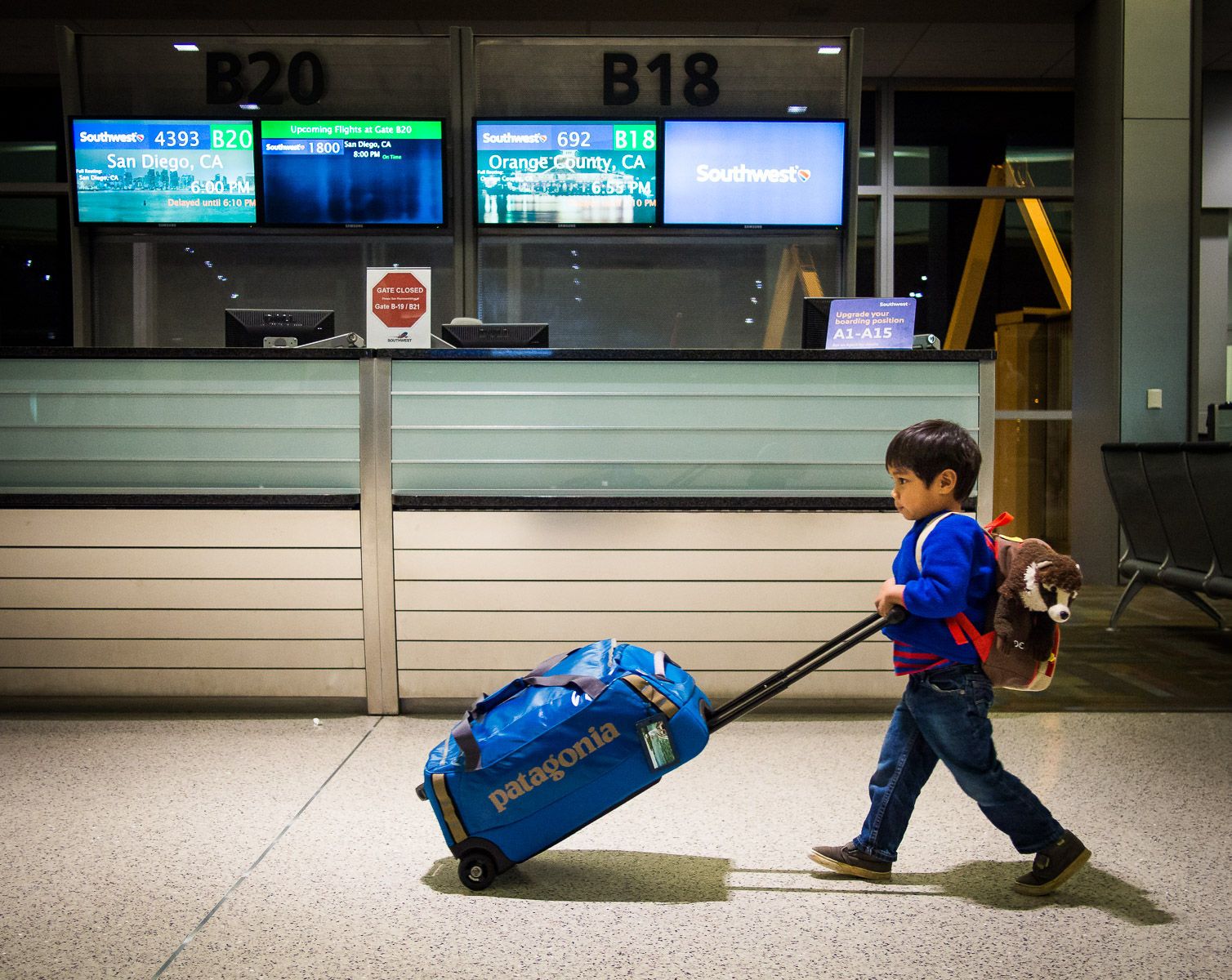 Young Boy and stuffed animal pushing luggage through the airport