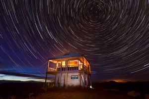 Werner Peak Lookout Tower glows under lantern light at night in the Stillwater State Forest, Montana, USA