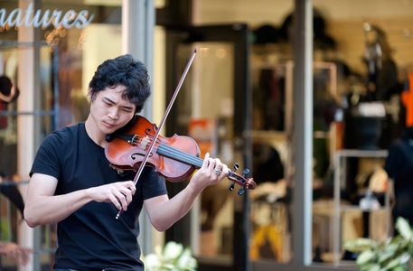 Street musician playing violin at promenade