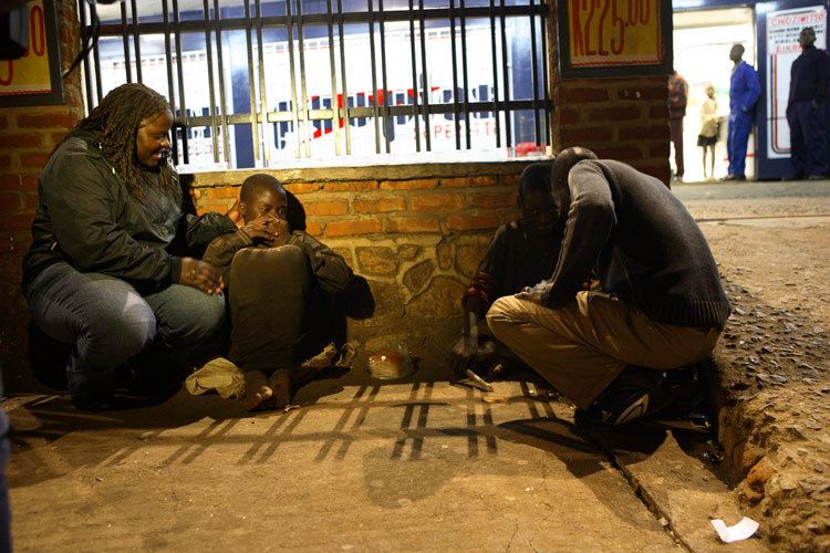 Irene and Auspicious, staff from the Chisomo Street Children project on night patrol in Lilongwe, Malawi. A hired Armed Police guard accompanies the team whilst they look for children sleeping rough on shop Verandahs, Markets, alleys,anywhere. Once found the young people are invited to visit Chisomo for food, a wash, support and counselling. 1malawi_street_child_6.jpg
