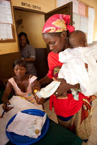 Mother and Child buy from pharmacist at Health clinic in Freetown Sierra Leone. medicine and healthcare should be free for the under fives and pregnant women, however often supplies finish and parents of sick children turn to the black market. Sierra Leone. 1sierra_leone_health_centre.jpg