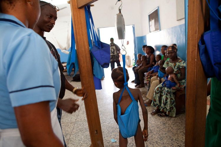 Five year old girl is weighed at The Therapeutic Feeding Centre Baby Clinic at Ola During Childrens Hospital. Mothers arrive and wait in line to have their children weighed before being given food supplements and advice on healthy eating for their children. Freetown, Sierra Leone. 1sierra_leone_child_health_14.jpg