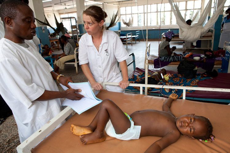 Catrin Boyle, Paediatric Nurse and VSO Volunteer working in the ICU (Intensive Care Unit) of Ola During Childrens Hospital, Freetown. Catrin is seen working alongside the Nurse in charge of the ICU, Prince Gbenda.Catrin and Prince attend to Yabum Kamara, 2yrs 8mths anaemic child who is having an emergency blood transfusion. Yabum was bought in by her mother after vomitting, coughing and running a fever for 5 days. Yabum shares her bed with another child patient due to lack of space. Sierra Leone for VSO. 1sierra_leone_hospital_child.jpg