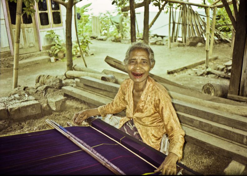 On the island of Adonara lives this tradional weaver in a very remotevillage up a volcano doing her traditional Ikat cloth the old way.She chews a mixture of Betel nut and lime a mild stimulant that stains the teeth red.