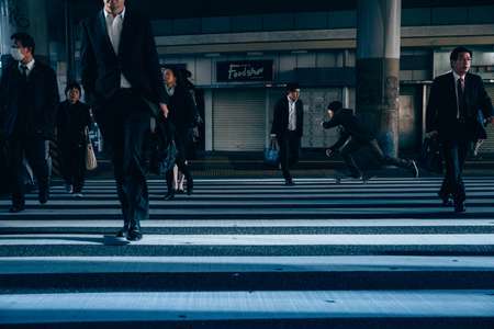 Jeremy Jones. Tokyo, Japan skating across a crosswalk of people going to work as businessman. Jeremy has perfect lighting on his face which makes this shot pop Skateboarder in Shibuya Japan