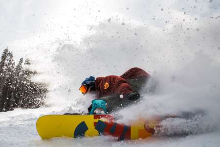 Ben Ferguson. Breckenridge, CO high speed carve turn close up in front of camera. Snow flies everywhere. Snowboard does a high speed carve