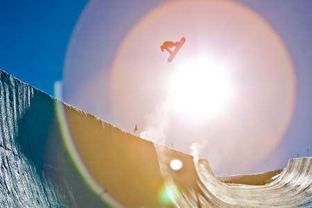 Shaun White. Park City, Utah. Flying high in the air out of the halfpipe in Park City. A giant sun flare is the in background making the shot look like an eyeball of light Shaun White flies out of the sun