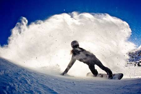 Shaun White. Mammoth, CA lays out a carve and a giant spray of snow is in the air. Shaun White lays out a turn