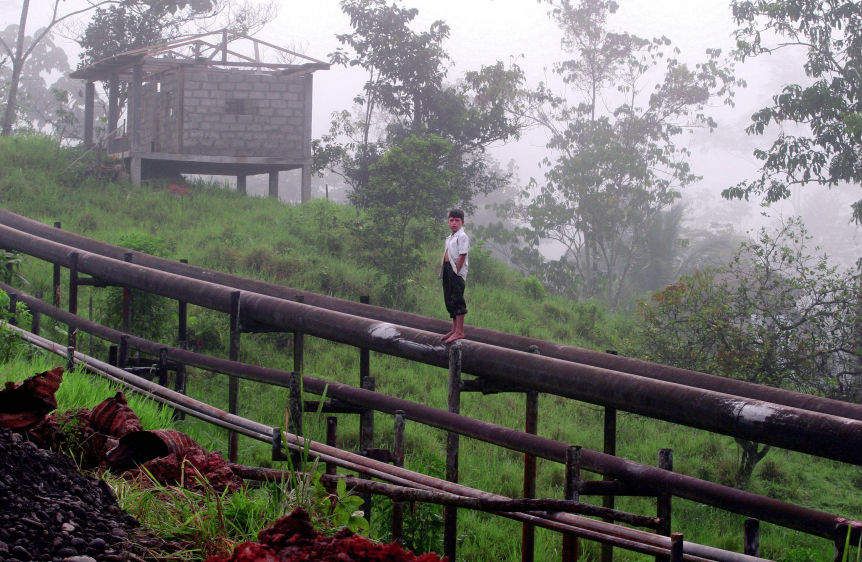 A boy stands on an oil pipeline built in the jungle near Lago Agrio.