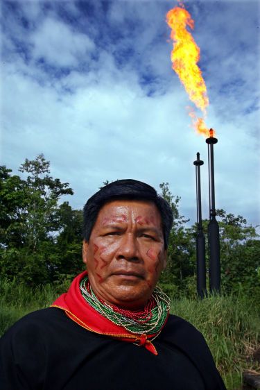 Cofan leader Emergildo Criollo stands in front of the flares of a separation plant in the Guanta oil fields. The plant was built by Texaco on Cofan ancestral territory.