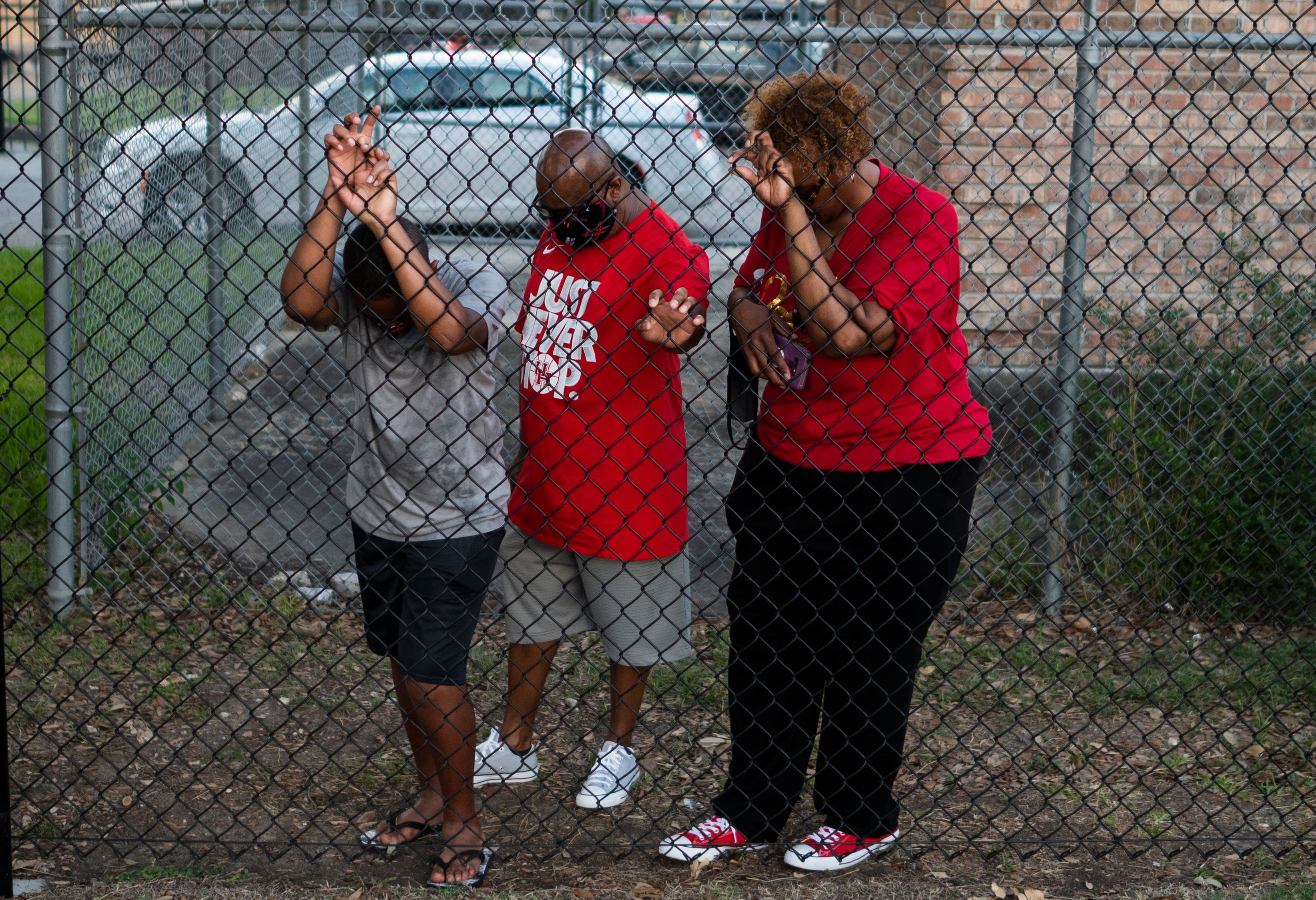 Visitors pray as they pay their respects to George Floyd during a candlelight vigil at Jack Yates High School. 1T434F.jpg
