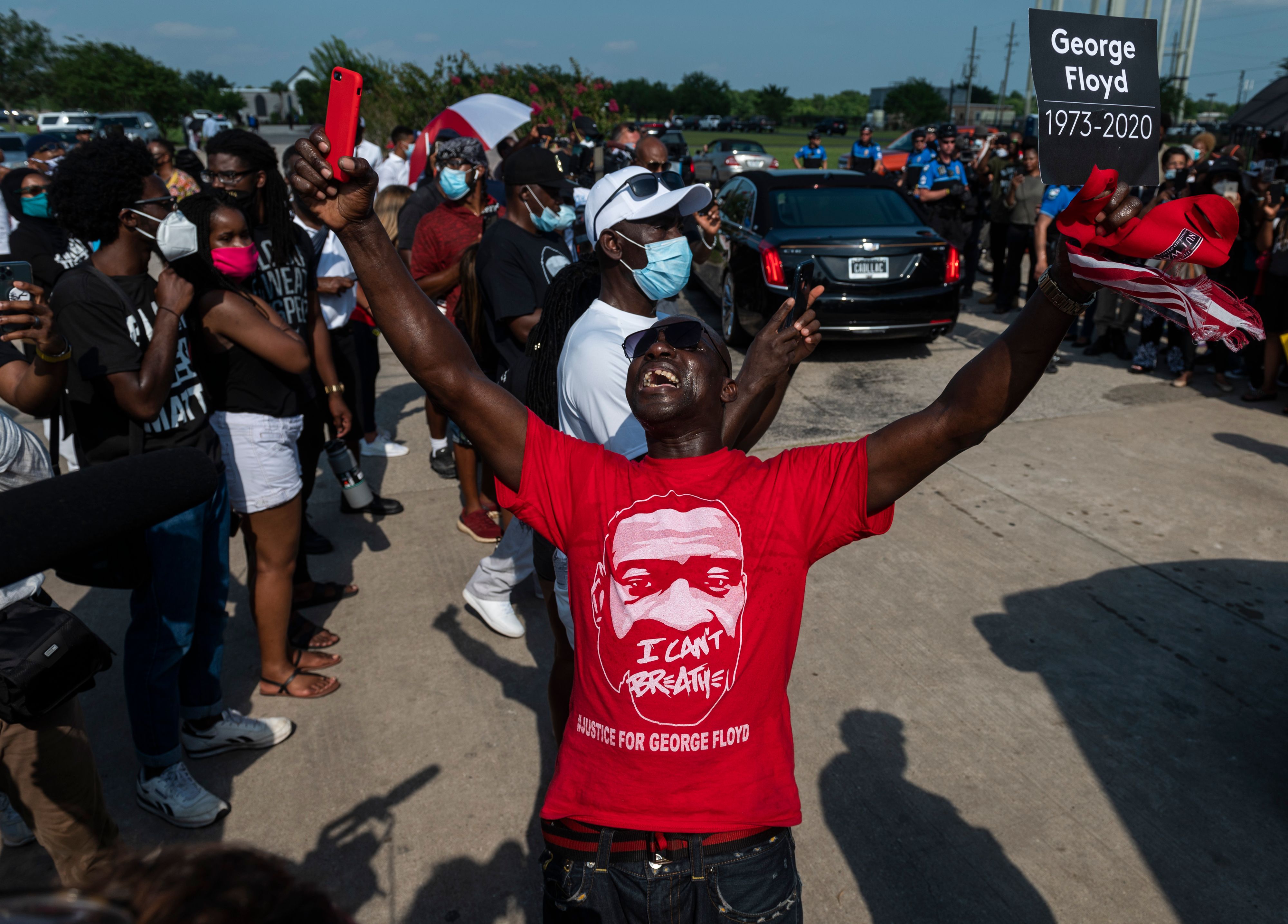 A man raises his hands as mourners watch the casket of George Floyd carried by a white horse-drawn carriage to his final resting place at the Houston Memorial Gardens, the culmination of a long farewell to the 46-year-old African American whose death in custody ignited global protests against police brutality and racism. 1T61JU.jpg