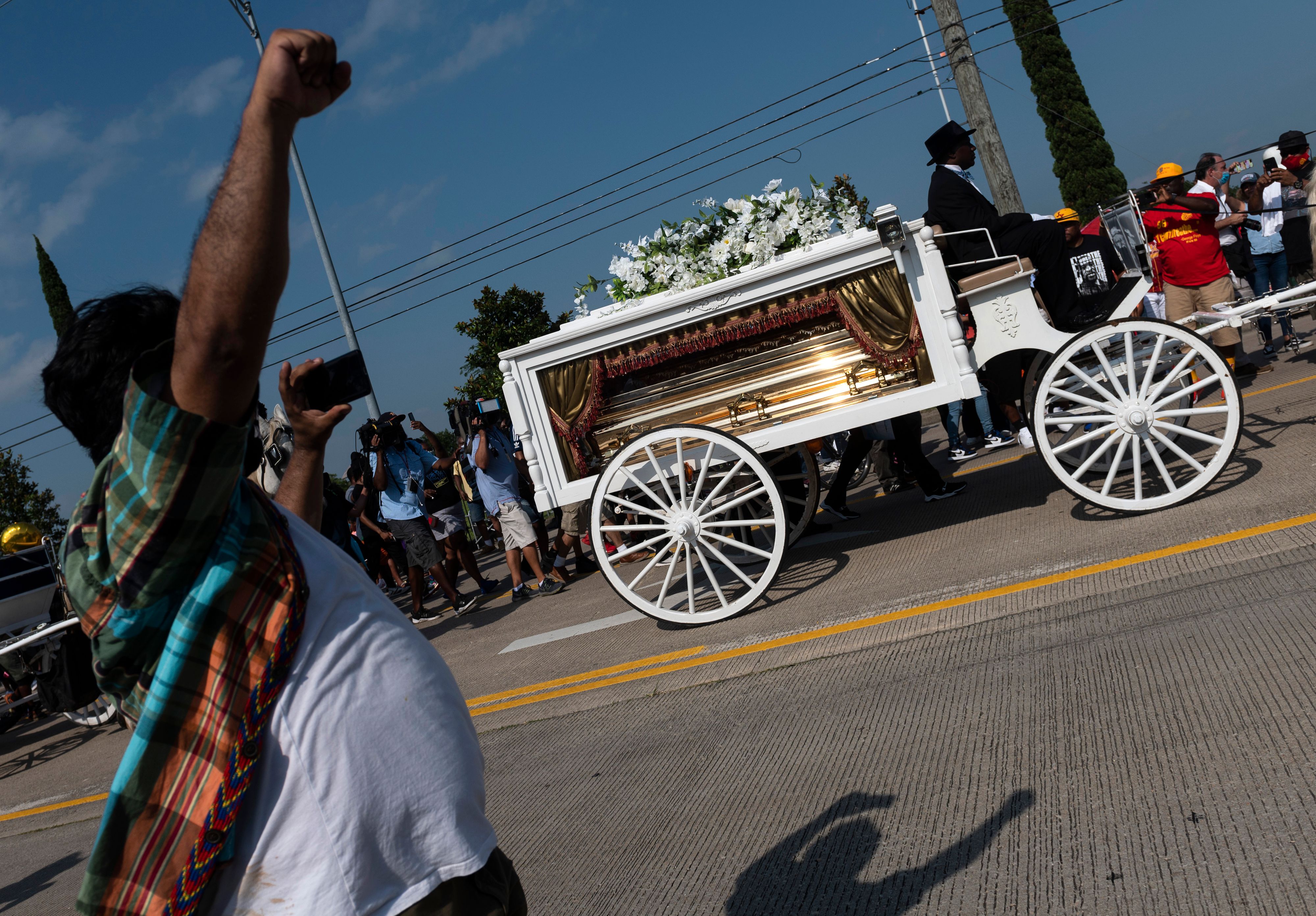 A man raises his fist as mourners watch the casket of George Floyd carried by a white horse-drawn carriage to his final resting place at the Houston Memorial Gardens, the culmination of a long farewell to the 46-year-old African American whose death in custody ignited global protests against police brutality and racism. 1T61JR.jpg