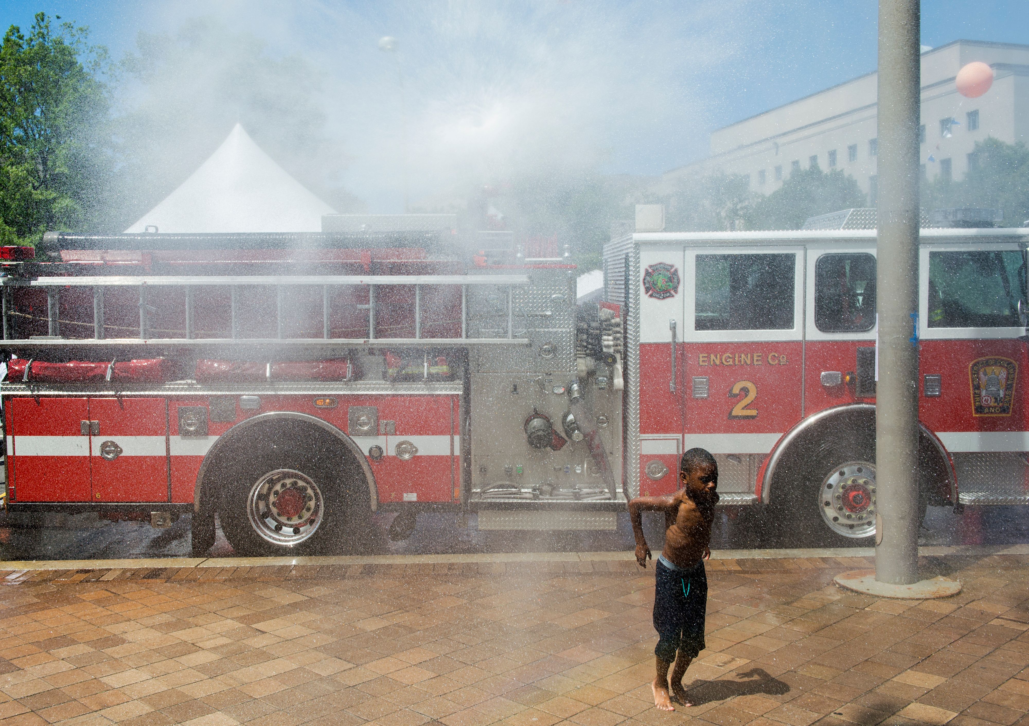 A young boy cools off in a spray from a fire truck in Washington, DC on June 12, 2016.
