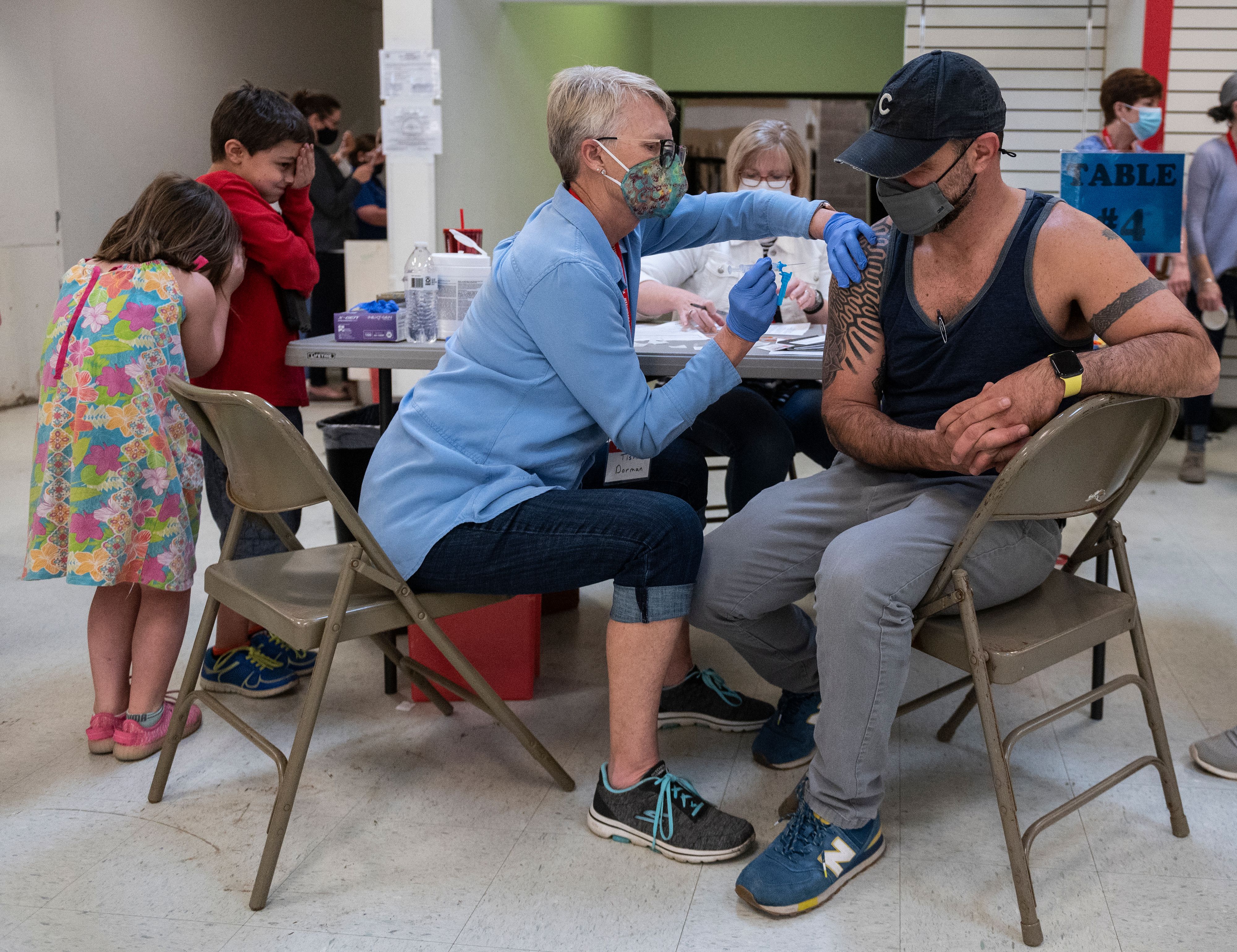Sean Alexander Bailey (R) gets a Covid-19 vaccination from his mother in law, Tish Dorman, as as his daughter Ella and son Charlie react at an old TJ Maxx store used by Lynchburg fire Department as a mass Covid-19 vaccination site in Lynchburg. 94X7KR.jpg