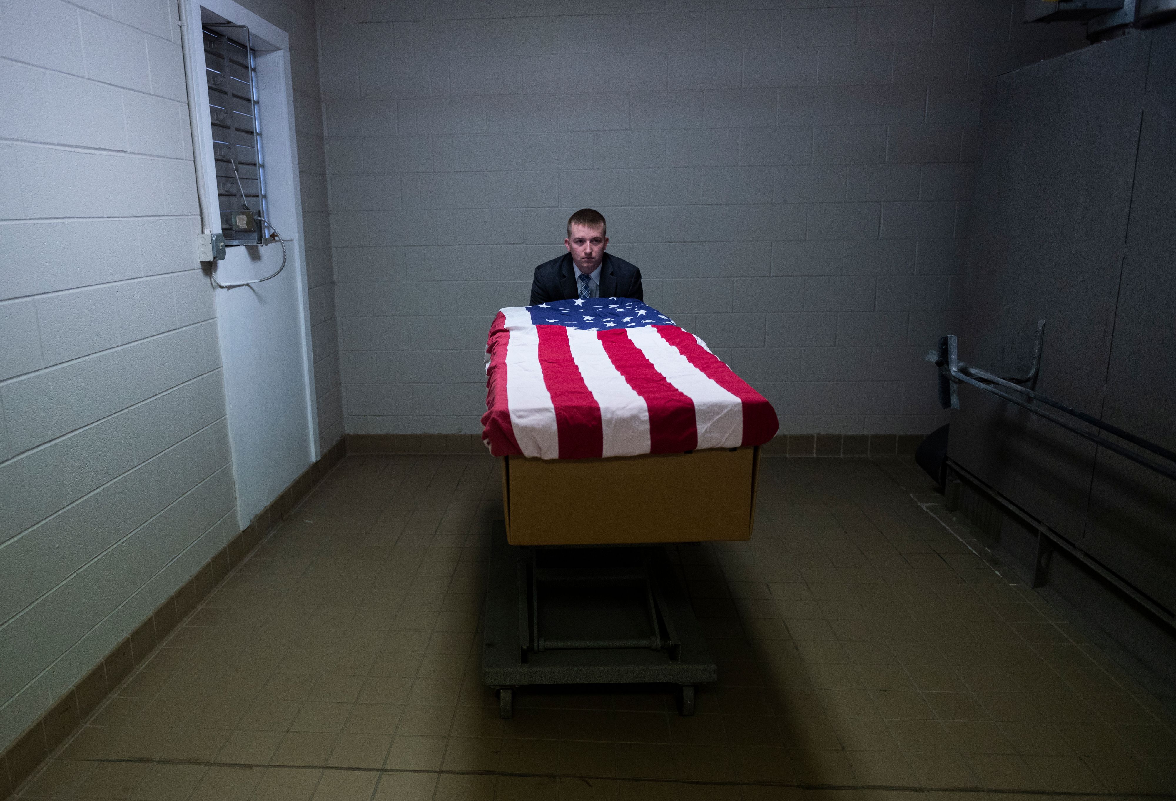 Crematory operator Brandon Cochran pushes a cremation box draped in a US national flag, containing the body a veteran who died of COVID-19, to an incinerator at the Stauffer Funeral Homes. 1QY3KY.jpg