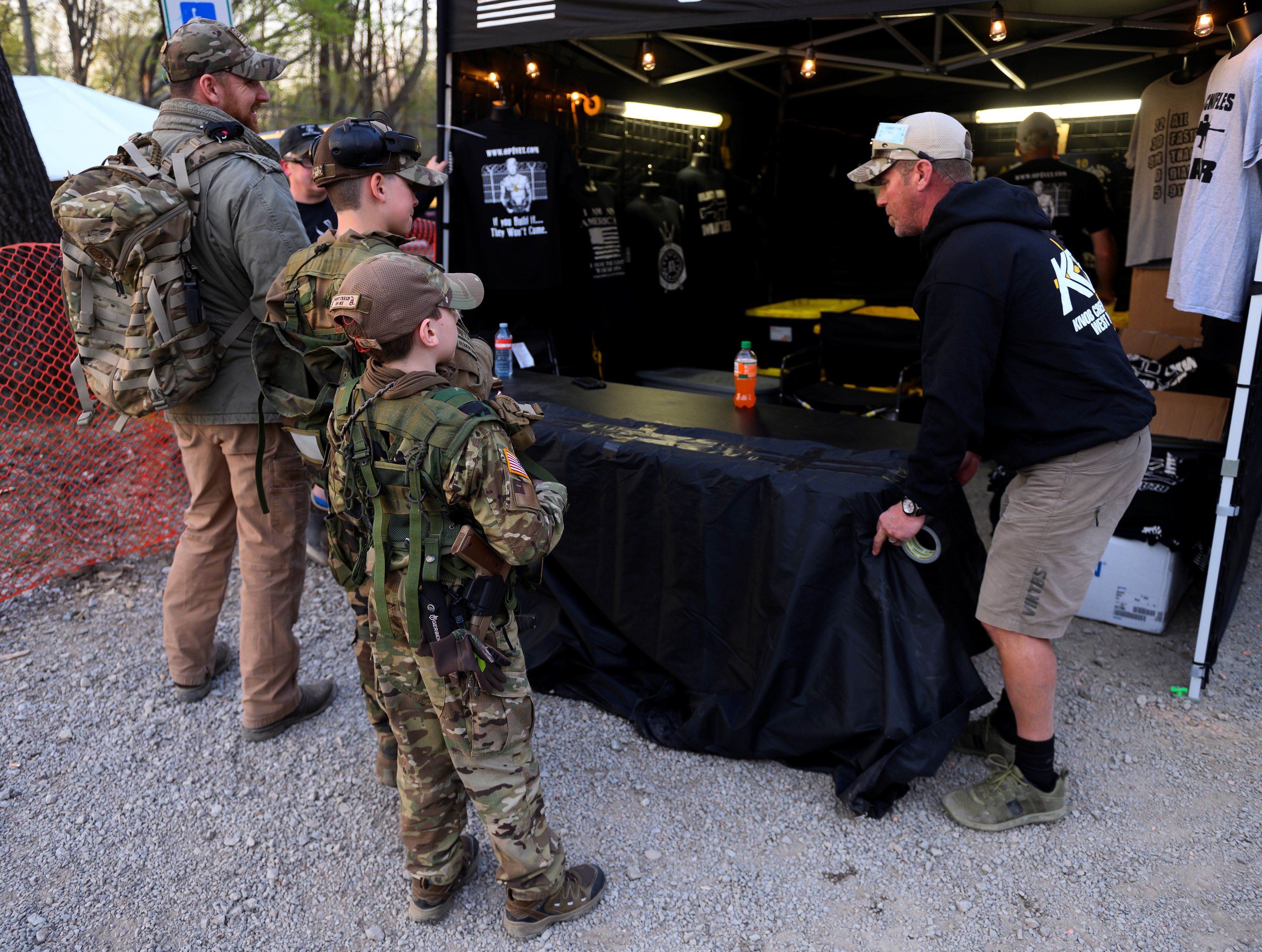 A father and his two sons speak with a vendor at the Knob Creek Machine Gun Shoot and Military Gun show . 1FM8CU.jpg