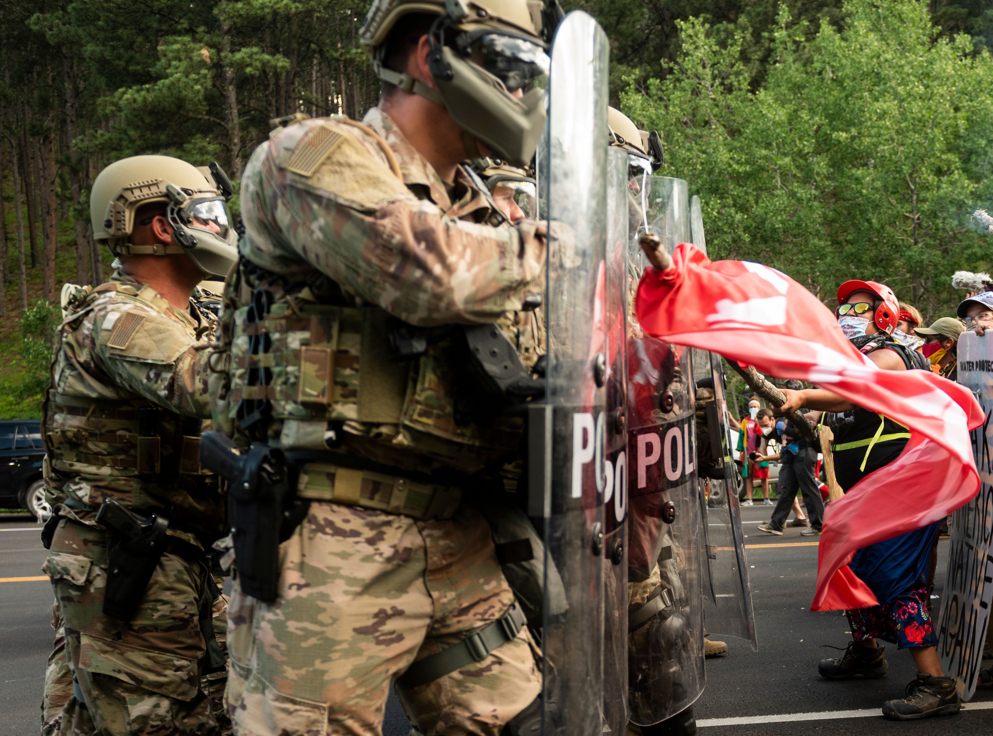 A protester hits the shields of National Guard troops as they block the road to Mount Rushmore National Monument with vans as they protest and confront police and military personnel in Keystone, South Dakota on July 3, 2020, during a demonstration around the Mount Rushmore National Monument and the visit of US President Donald Trump. 1UL0RQ.jpg