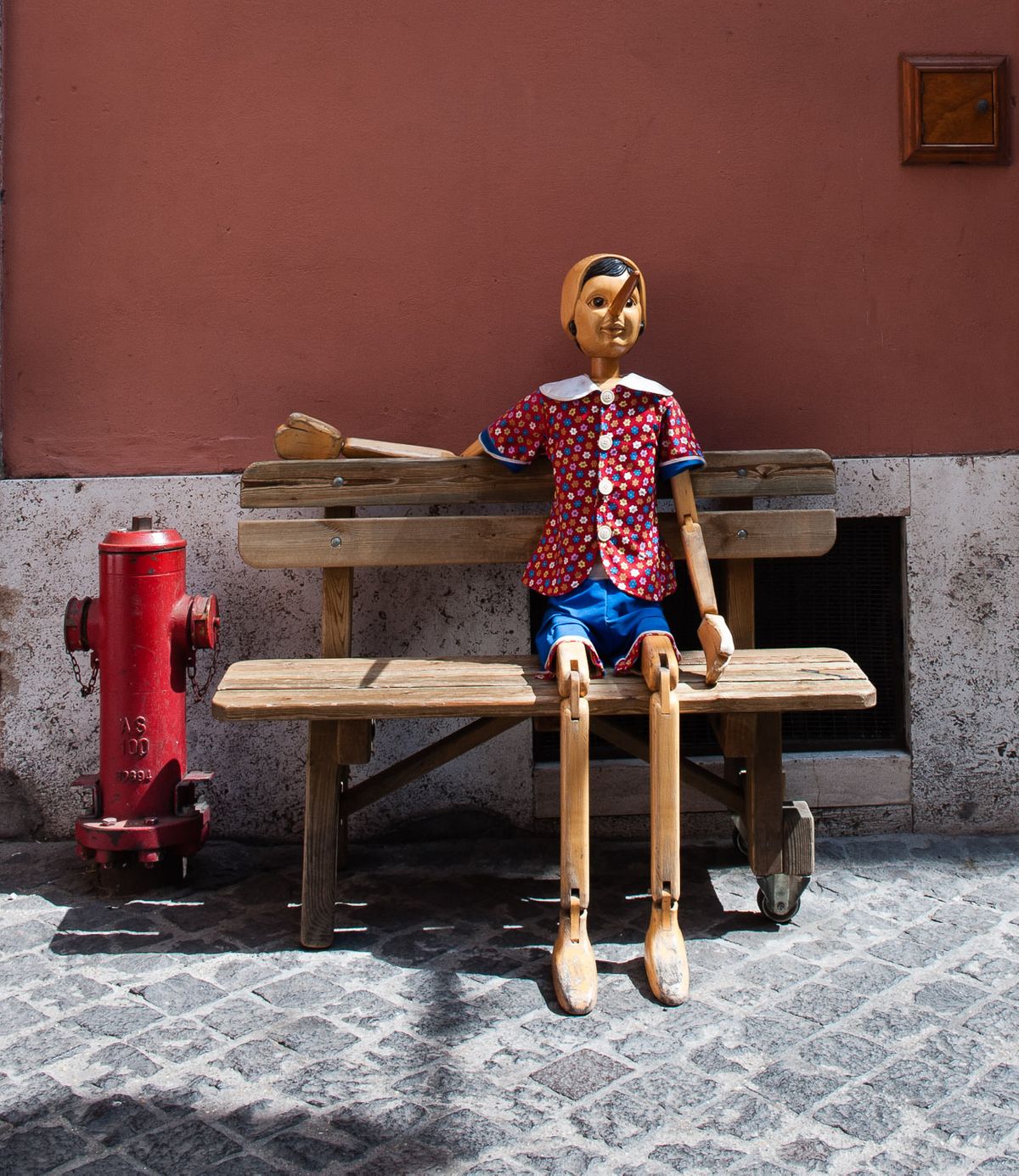 Pinocchio puppet sitting on bench.