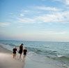 Picture of three children holding hands and walking down the beach