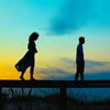 Image of two teenager siblings walking on boardwalk rail at sunrise