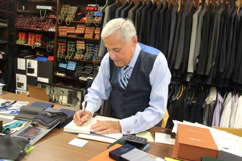 Martin Greenfield Clothiers, Ltd. is a Brooklyn manufacturer of hand tailored men’s clothing. The Company was founded in 1977 by Martin Greenfield when he bought the factory from his former employer, GGG Clothes. Mr. Greenfield had joined GGG in 1947 as an entry-level floor boy, ultimately rising to Vice President of Production before buying out his former employer.  Initially structured as a traditional manufacturer; currently, Martin Greenfield Clothiers is focused on a hybrid approach. We construct garments to meet the requirements of innovative designers, specialty retailers, costume designers, stylists and individuals. We hand craft the finest made-to-order as well as made-to-measure suits, tuxedoes, sport jackets, slacks, and overcoats 100% built by hand in our 1917 Brooklyn Factory.  Martin's sons Jay and Tod Greenfield joined their father in the 1980s and the trio currently manages the Company. We keep our focus on production, not promotion, creating garments with built in intrinsic value.  Martin Gre Martin Greenfield signing the book about his legacy.