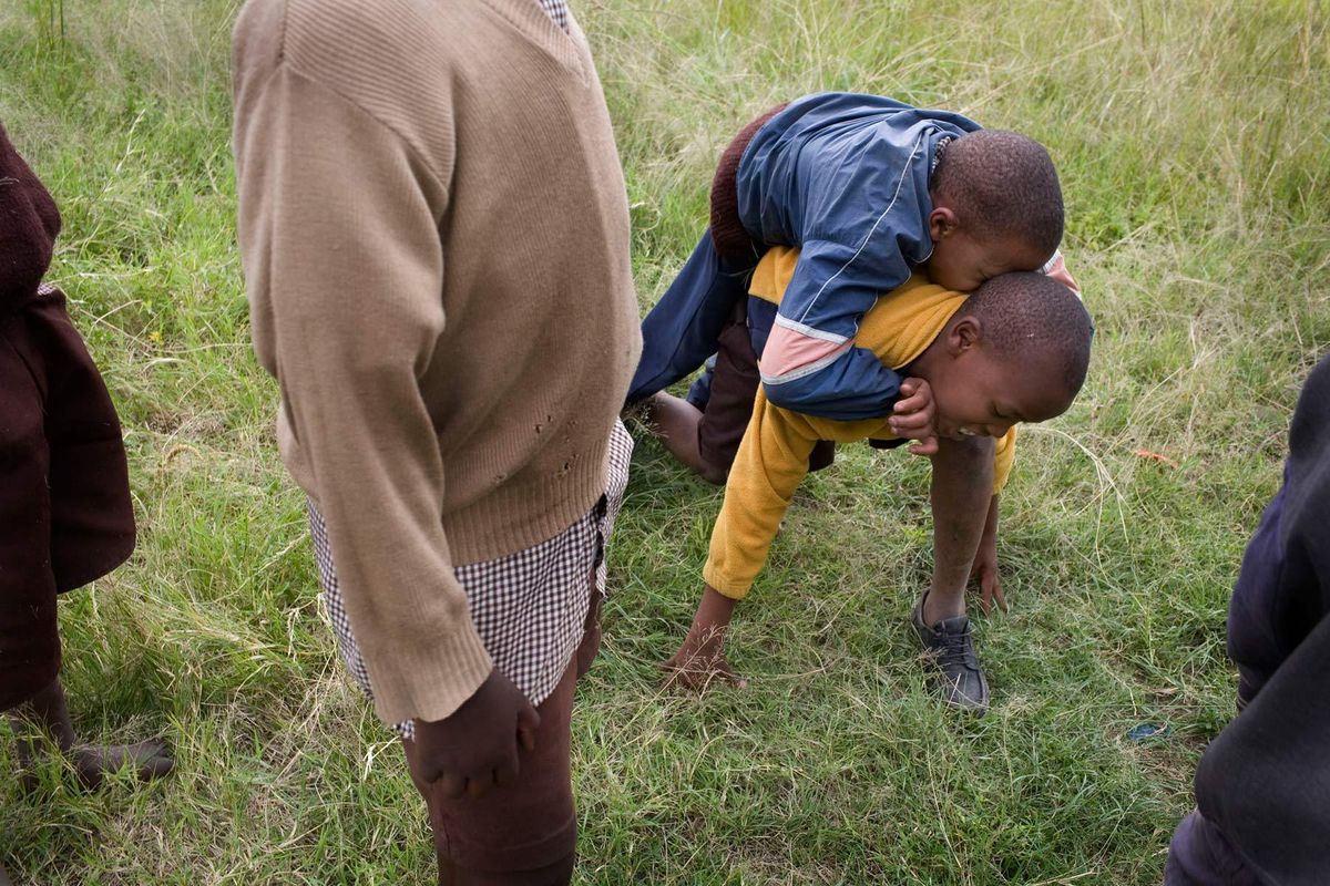 Mutava getting into position for Braise to climb onto his back so he can carry him home from school at the end of the day.© Hazel Thompson Carried on friendship