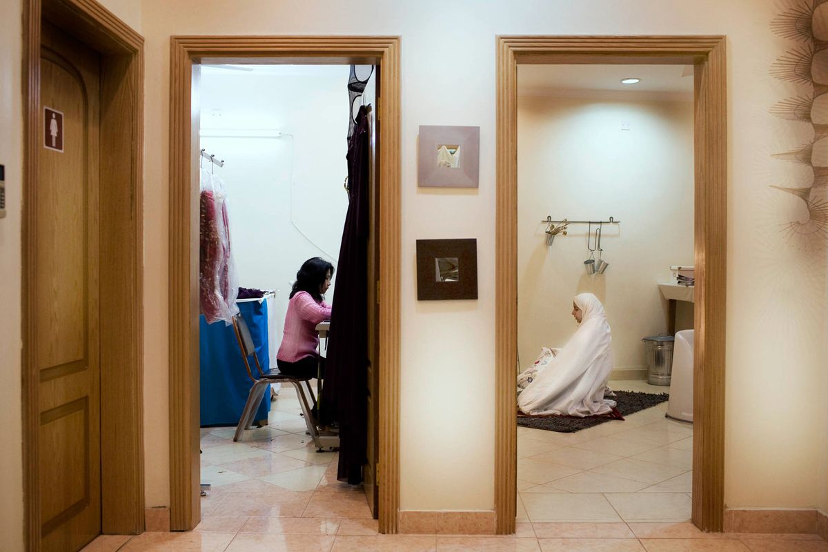 Sima, fashion designer aged 35 doing her mid-day prayers in her office, while her staff continues to work in the other room in Bahrain.© Hazel Thompson Measure of a Woman