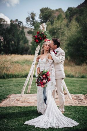 Groom Kissing Bride in Front of Backdrop Ceremony