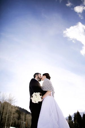 Kissing with a Frosty Blue Sky Backdrop Bride and Groom