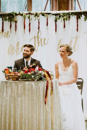 Bride and Groom Seated at Head Table with Vibrant Centerpiece Reception