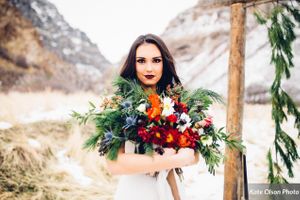 Hoopes Events | Romantic Winter-Styled Shoot | Bride with Flowers Beside Evergreen-Draped Backdrop Romantic_Winter_Shoot_Bride_Evergreen-Draped_Backdrop.jpg