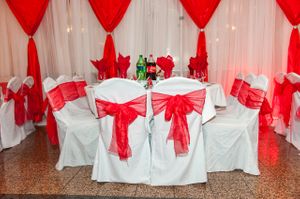 White Table Linens and Chair Covers with Red Sashes and Wall Draping Details