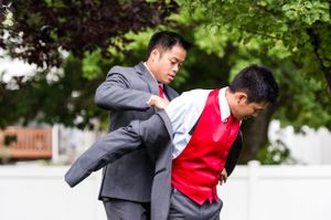Groomsman Helps Groom Put On Suit Groom and Groomsmen