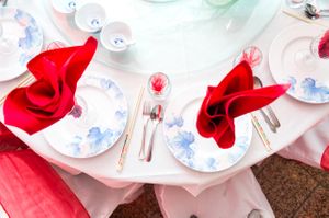 Place Settings With Red Napkins and White Plates With Blue Florals Details