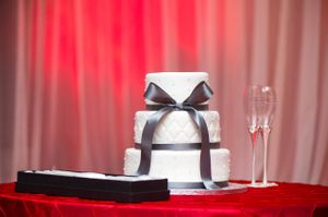 White Cake With Black Ribbon On Rich Red Tablecloth Details