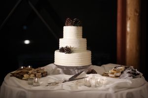 Tastefully Decorated Wedding Cake Table with Pine Cone Decor Wedding Cake